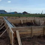 Строительство дома «Данияр» 130 м² в Астане, 2026: смонтированная деревянная опалубка ленточного фундамента, общий вид площадки HotWell.kz