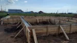 Строительство дома «Данияр» 130 м² в Астане, 2026: смонтированная деревянная опалубка ленточного фундамента, общий вид площадки HotWell.kz