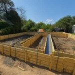 Строительство дома «Марк» 130 м² в посёлке Алатау, 2026: залитый ленточный фундамент в опалубке, общий вид площадки HotWell.kz