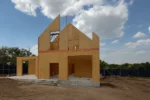 Дом «Игорь» 200 м², Талгар, 2026: коробка вышла на полную высоту — стены второго этажа и фронтоны из СИП-панелей собраны, установлена коньковая балка, панели раскреплены временными подкосами