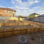 Дом «Сатурин» 165 м², Алматы, 2026: по пятну застройки собрана деревянная опалубка ленточного фундамента, размечены внутренние ленты под несущие стены, выставлена арматура и стяжки опалубки