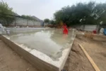 Дом «Сатурин» 165 м², Алматы, 2026: угол плиты после заливки стяжки — ровная бетонная поверхность по всей захватке, по краю виден слой утеплителя под стяжкой