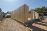 Дом «Сатурин» 165 м², Алматы, 2026: длинная наружная стена собрана по периметру плиты, цоколь фундамента обмазан гидроизоляцией