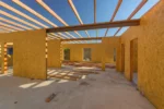 Дом «Сатурин» 165 м², Алматы, 2026: вид вдоль дома изнутри — балки перекрытия опираются на стальной прогон, по стяжке выведены гильзы под коммуникации