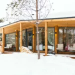 Проект дома «М-60» из СИП-панелей, 60 м² — одноэтажный дом с деревянной крытой террасой и панорамными окнами зимой | HotWell.KZ