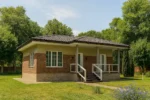 Проект бани «С-60» из СИП-панелей, 60 м² — одноэтажная баня с кирпичным фасадом, темной крышей и крытым крыльцом | HotWell.KZ
