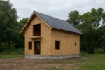 Дом «Б-117», 117 м², 1.5 этажа, в черновой отделке: коробка из СИП-панелей OSB-3, двускатная кровля из металлочерепицы, проёмы без окон и дверей, в проёмах видны сосновые балки перекрытия