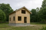 Дом «Б-120Б», 120 м², 1.5 этажа, в черновой отделке: коробка из СИП-панелей OSB-3, двускатная кровля из металлочерепицы, проёмы без окон и дверей, в проёмах видны сосновые балки перекрытия