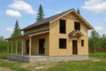 Дом «Б-131Б», 131 м², 1.5 этажа, в черновой отделке: коробка из СИП-панелей OSB-3, двускатная кровля из металлочерепицы, проёмы без окон и дверей, в проёмах видны сосновые балки перекрытия