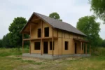 Дом «Б-160Г», 160 м², 1.5 этажа, в черновой отделке: коробка из СИП-панелей OSB-3, двускатная кровля из металлочерепицы, проёмы без окон и дверей, в проёмах видны сосновые балки перекрытия