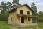 Дом «Д-173», 173 м², 1.5 этажа, в черновой отделке: коробка из СИП-панелей OSB-3, двускатная кровля из металлочерепицы, проёмы без окон и дверей, в проёмах видны сосновые балки перекрытия