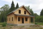 Дом «К-183Б», 183 м², 1.5 этажа, в черновой отделке: коробка из СИП-панелей OSB-3, двускатная кровля из металлочерепицы, проёмы без окон и дверей, в проёмах видны сосновые балки перекрытия