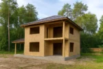Дом «Л-178», 178 м², 2 этажа, в черновой отделке: коробка из СИП-панелей OSB-3, вальмовая кровля из металлочерепицы, проёмы без окон и дверей, в проёмах видны сосновые балки перекрытия
