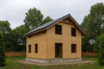 Дом «М-114», 114 м², 1.5 этажа, в черновой отделке: коробка из СИП-панелей OSB-3, двускатная кровля из металлочерепицы, проёмы без окон и дверей, в проёмах видны сосновые балки перекрытия
