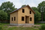 Дом «О-118Б», 118 м², 1.5 этажа, в черновой отделке: коробка из СИП-панелей OSB-3, двускатная кровля из металлочерепицы, проёмы без окон и дверей, в проёмах видны сосновые балки перекрытия