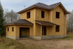 Дом «Р-160», 160 м², 2 этажа, в черновой отделке: коробка из СИП-панелей OSB-3, вальмовая кровля из металлочерепицы, проёмы без окон и дверей, в проёмах видны сосновые балки перекрытия