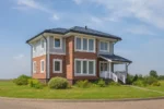 Проект дома «Т-112В» из СИП-панелей, 112 м² — двухэтажный дом с кирпичным фасадом, синей крышей и крыльцом | HotWell.KZ