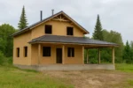 Дом «Т-134», 134 м², 1.5 этажа, в черновой отделке: коробка из СИП-панелей OSB-3, двускатная кровля из металлочерепицы, проёмы без окон и дверей, в проёмах видны сосновые балки перекрытия