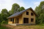 Дом «Т-136», 136 м², 1.5 этажа, в черновой отделке: коробка из СИП-панелей OSB-3, двускатная кровля из металлочерепицы, проёмы без окон и дверей, в проёмах видны сосновые балки перекрытия
