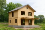 Дом «Т-153Б», 153 м², 2 этажа, в черновой отделке: коробка из СИП-панелей OSB-3, двускатная кровля из металлочерепицы, проёмы без окон и дверей, в проёмах видны сосновые балки перекрытия