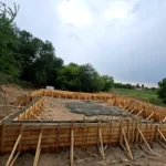 Строительство цеха «Евгений» в мкр Шанырак (Алматы), 2026: опалубка ленточного фундамента с заливкой бетоном, общий вид площадки HotWell.kz