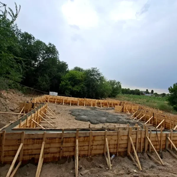 Строительство цеха «Евгений» в мкр Шанырак (Алматы), 2026: опалубка ленточного фундамента с заливкой бетоном, общий вид площадки HotWell.kz
