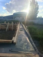 Строительство дома «Пётр» 54 м² в Каскелене, 2026: залитая бетоном лента фундамента в деревянной опалубке, на фоне предгорья Заилийского Алатау