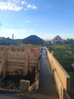 Дом «Пётр» 54 м², Каскелен, 2026: вид вдоль залитой ленты фундамента, щиты опалубки и распорки по всей длине