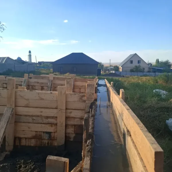 Дом «Пётр» 54 м², Каскелен, 2026: вид вдоль залитой ленты фундамента, щиты опалубки и распорки по всей длине