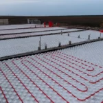 Общежитие «Доссан» 550 м², Астана, 2026: по плите разложены белые маты с бобышками, в них уложены контуры тёплого пола из красной трубы, между блоками — разделительные рейки и выпуски арматуры