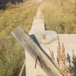 Строительство дома «Думан» 140 м² под Астаной, 2026: участок перед стартом — на месте старый ленточный фундамент, заросший травой, вдоль него лежит доска, рядом соседние дома