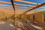Дом «Сатурин» 165 м², Алматы, 2026: внутри дома — комнаты сформированы стенами из СИП-панелей, над ними уложены балки перекрытия, на полу сложен запас бруса